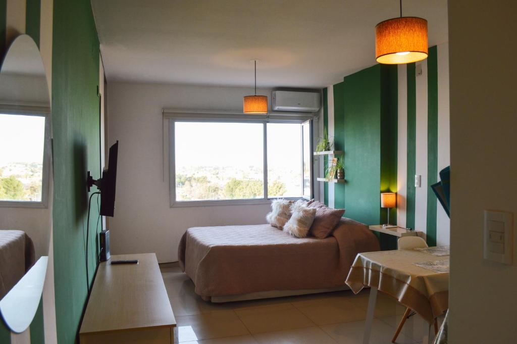 Habitación verde con cama y ventana en Dolce Casa Departamentos en Neuquén