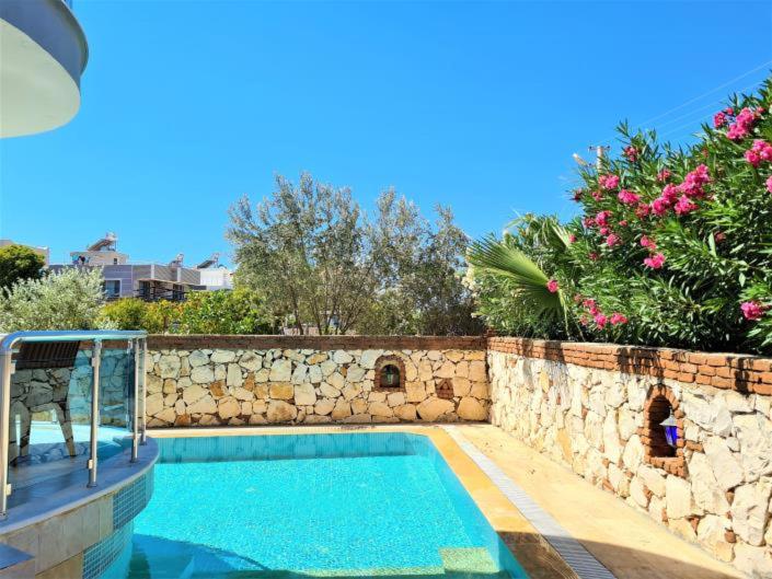 a swimming pool next to a stone wall at Three Bed villa, Private Pool in Didim