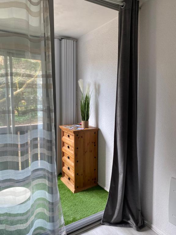 a room with a window and a dresser with a plant on it at Studio La Baleine Rose Centre Cap D'Agde in Cap d'Agde