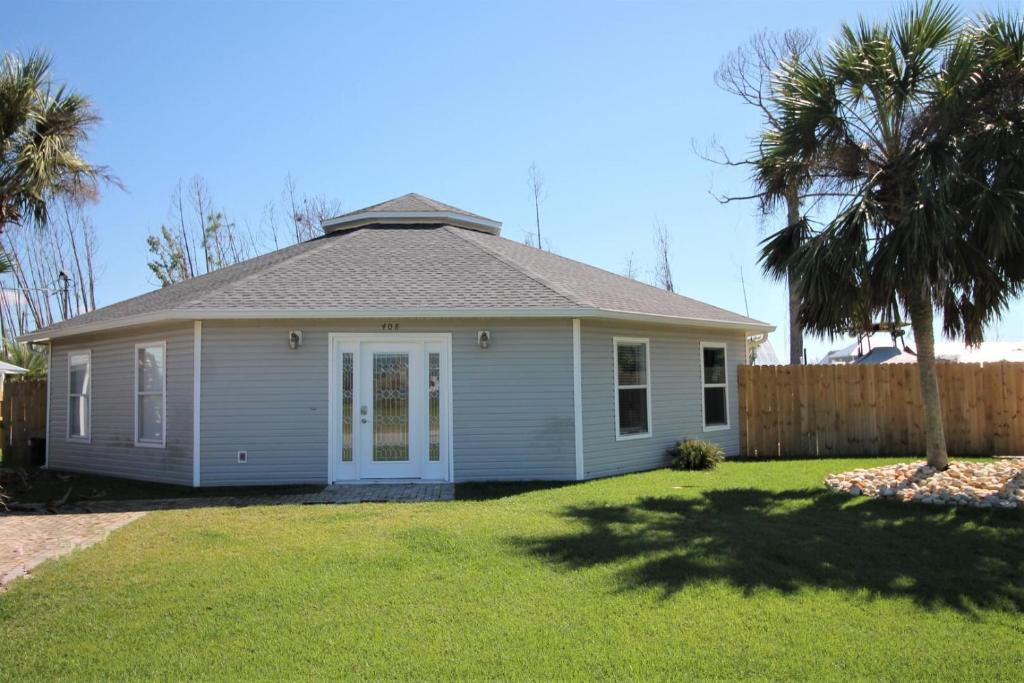 a small house with a palm tree in a yard at The Sand Dollar in Mexico Beach