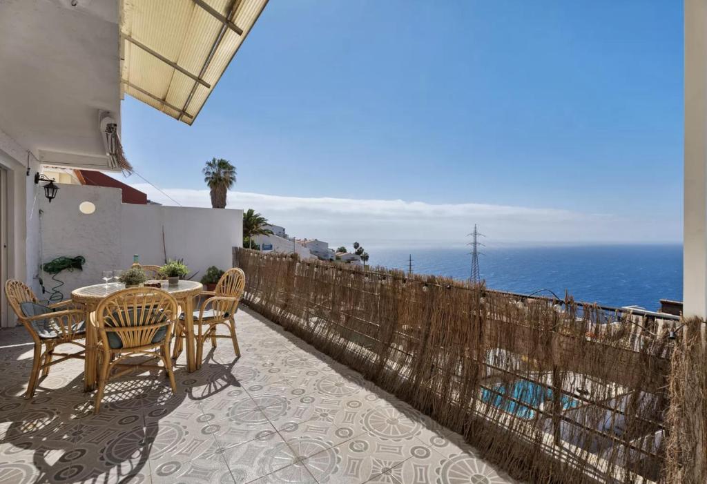 un patio con mesa, sillas y el océano en Tabaiba Sunset sea Views en Santa Cruz de Tenerife