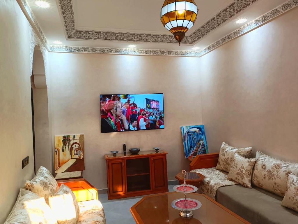 sala de estar con sofá y TV en la pared en Oasis appart sérénité, en Marrakech