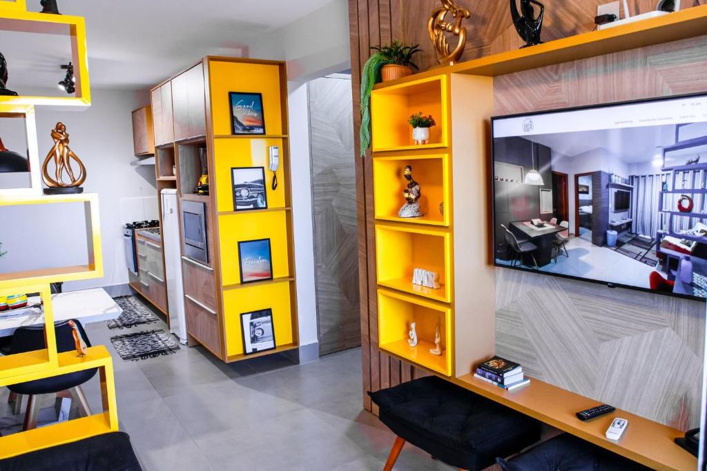 a living room with yellow shelves and a flat screen tv at Apartamento Aconchegante próximo ao Shopping Pantanal in Cuiabá