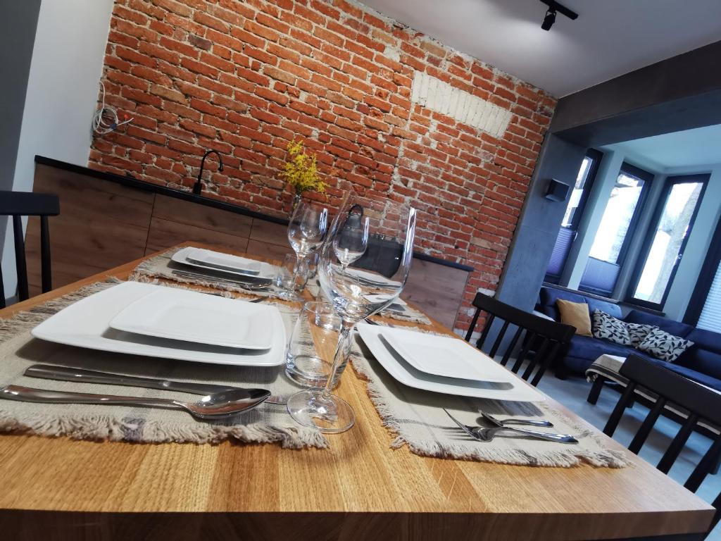 een houten tafel met borden en wijnglazen erop bij Apartament nr 2 w Starym Nadleśnictwie in Kościerzyna