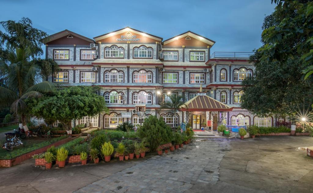 un grand bâtiment avec des arbres devant lui dans l'établissement Avocado Orchid Resort, à Heṭauḍā