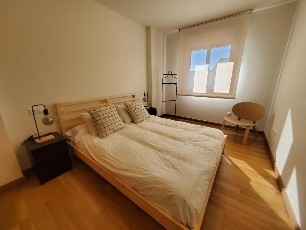 ein Schlafzimmer mit einem großen Bett und einem Fenster in der Unterkunft Apartamento con piscina a escasos metros de A Lanzada in Pontevedra