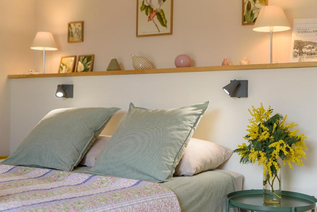um quarto com uma cama e um vaso de flores sobre uma mesa em Boulevard du Soleil em Bormes-les-Mimosas