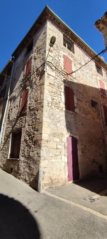 un ancien bâtiment en briques avec une porte et des fenêtres roses dans l'établissement LA JOVINE 2 Sault, à Sault