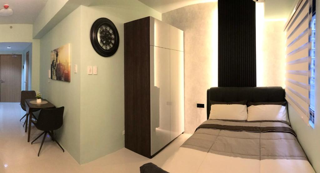 1 dormitorio con 1 cama y reloj en la pared en MOA Pasay, Shore 3 Residences - Modern Luxury Condo, en Manila