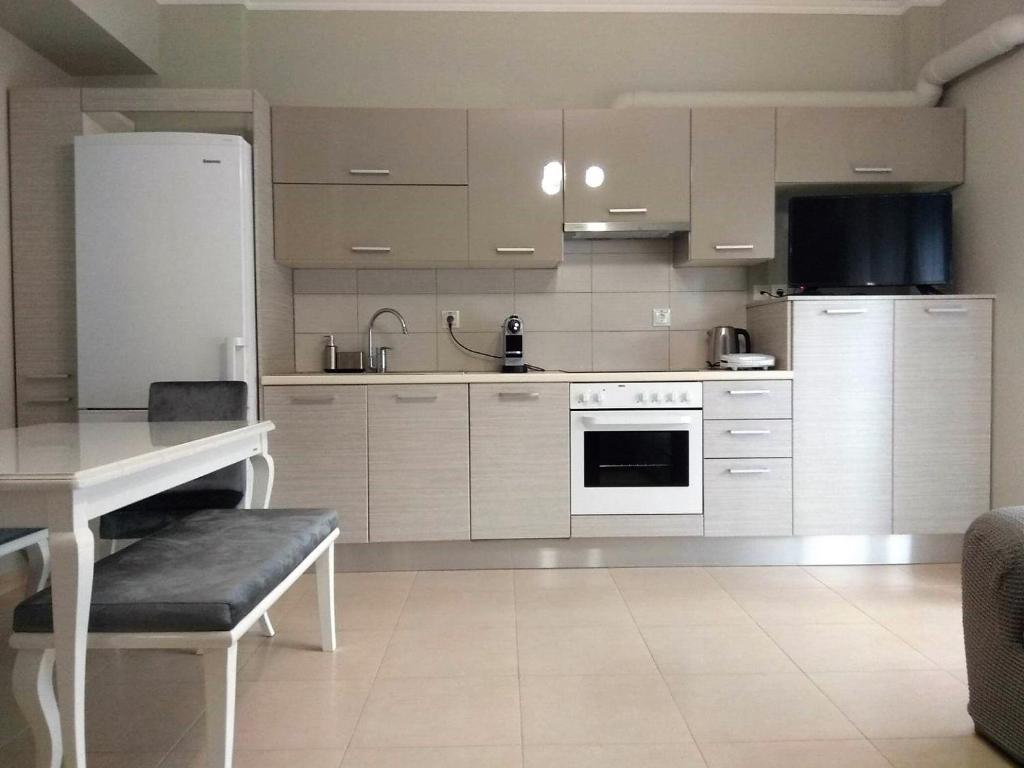 a kitchen with white cabinets and a table and a refrigerator at Lefkada CP Residences in Lefkada Town