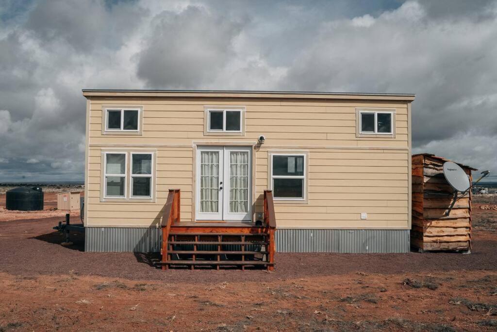 a yellow house with a porch and a house at Grand Canyon Hideaway Tiny home in Valle