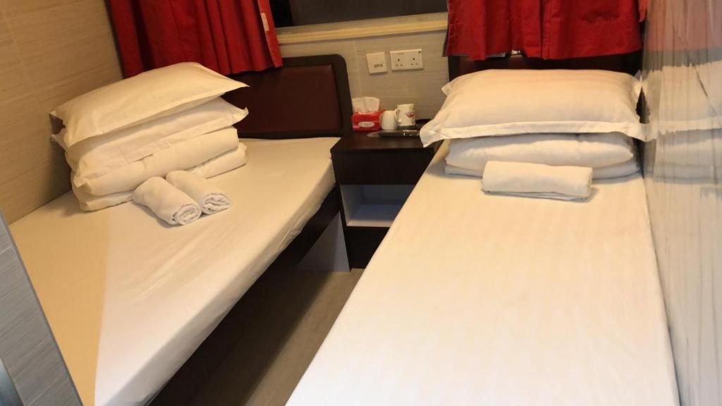 2 camas en una habitación de hotel con toallas en 富都賓館 Fu Dou Guest House, en Hong Kong