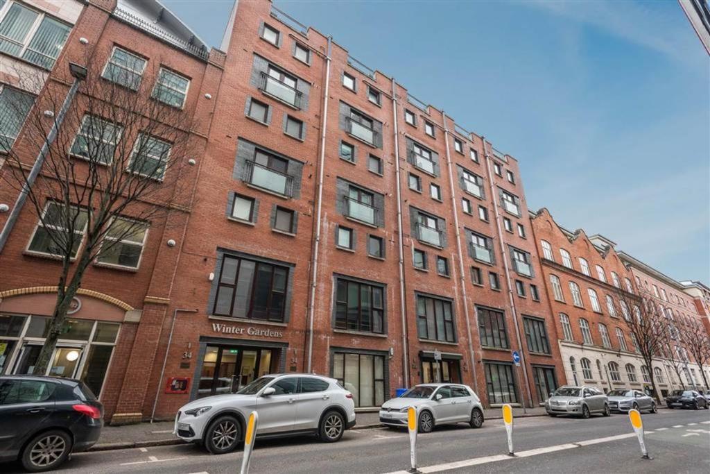 un gran edificio de ladrillo con coches estacionados frente a él en Modern Hut in Belfast, en Belfast