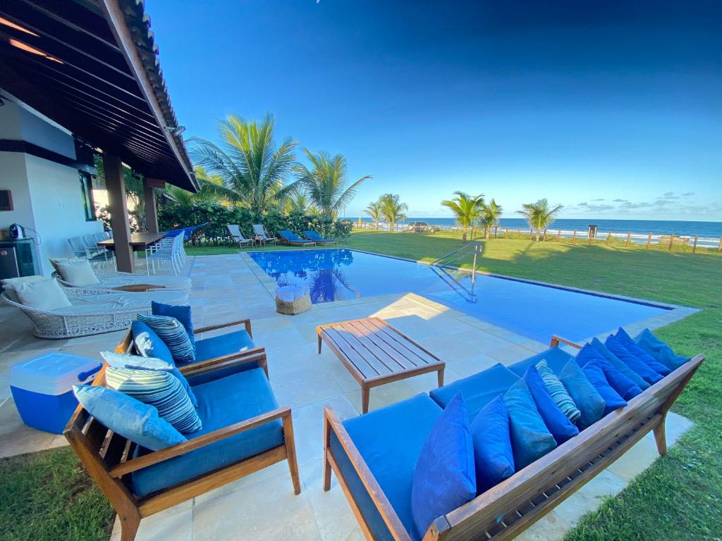 a swimming pool with blue cushioned chairs and a swimming pool at Bangalô Porto Galinhas in Porto De Galinhas