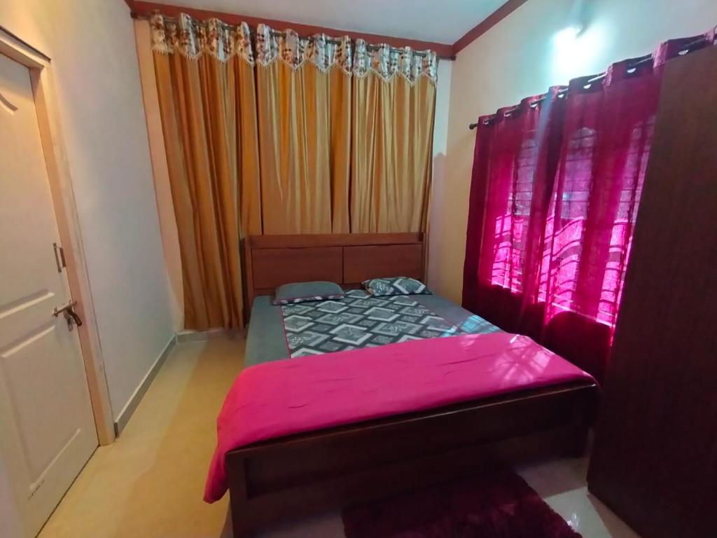 a bedroom with a bed with pink sheets and curtains at Snowdrop inn coorg in Madikeri