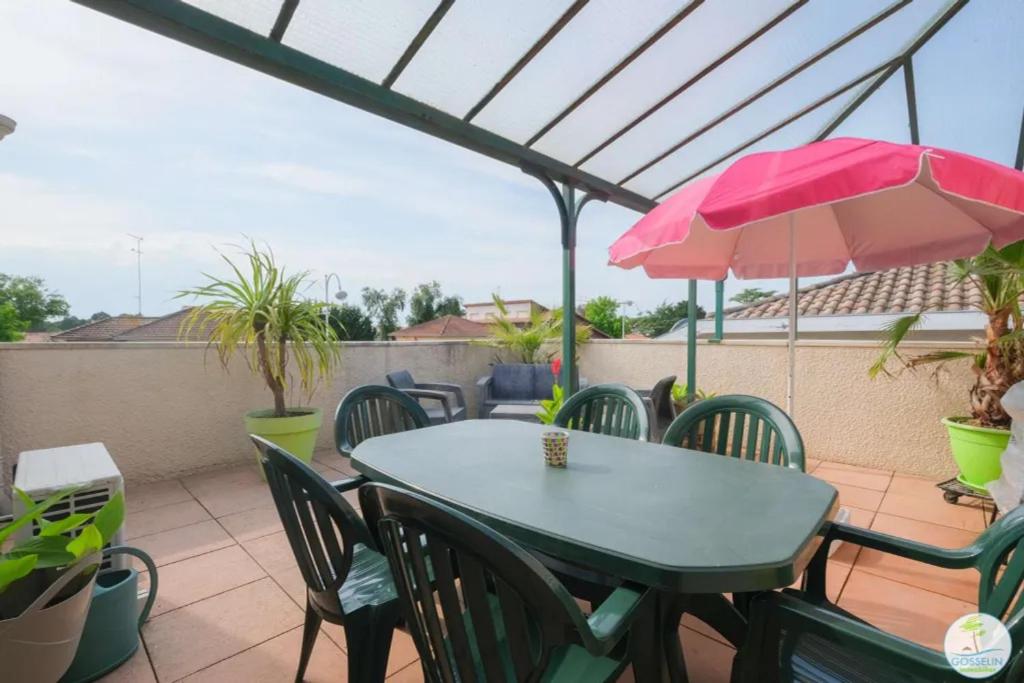 a patio table with chairs and a pink umbrella at Biscarrosse Bourg Appartement avec terrasse classé 1 étoile pour 4 personnes in Biscarrosse