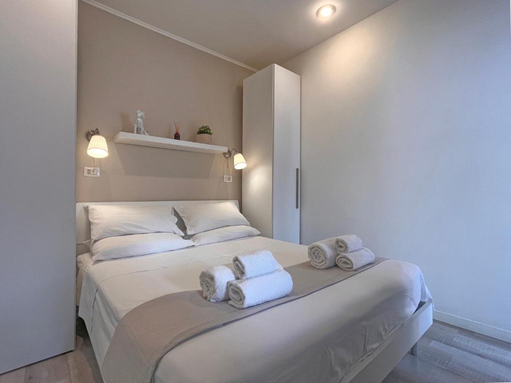 Un dormitorio con una cama blanca con toallas. en DMC Residence - Alloggi Turistici en Anzio