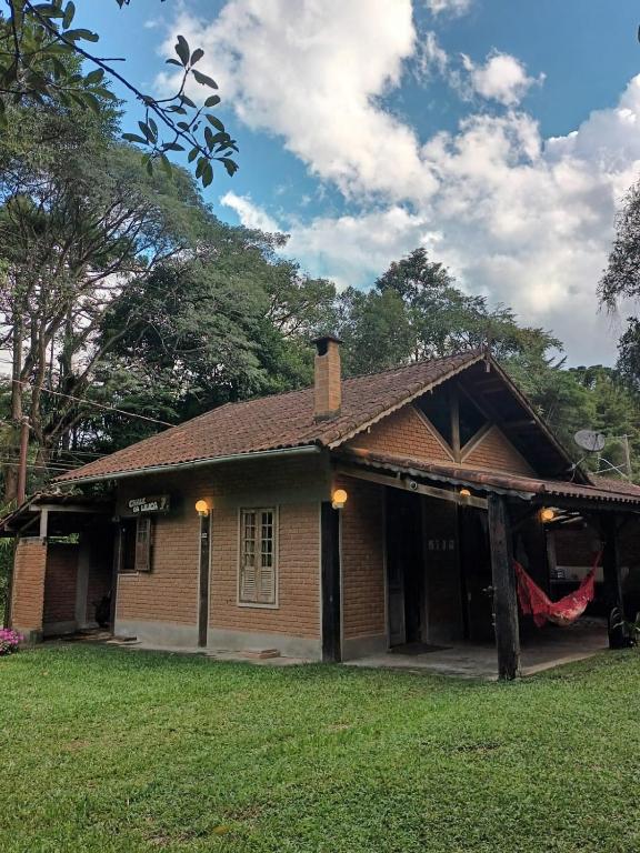 a small brick house with a lush green yard at Casa da Lilica in Visconde De Maua
