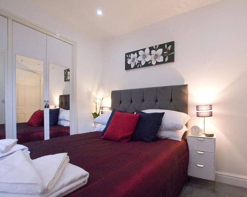 a bedroom with a large bed and a mirror at Cosy 1 Bedroom Apartment - Newbury High Street in Newbury