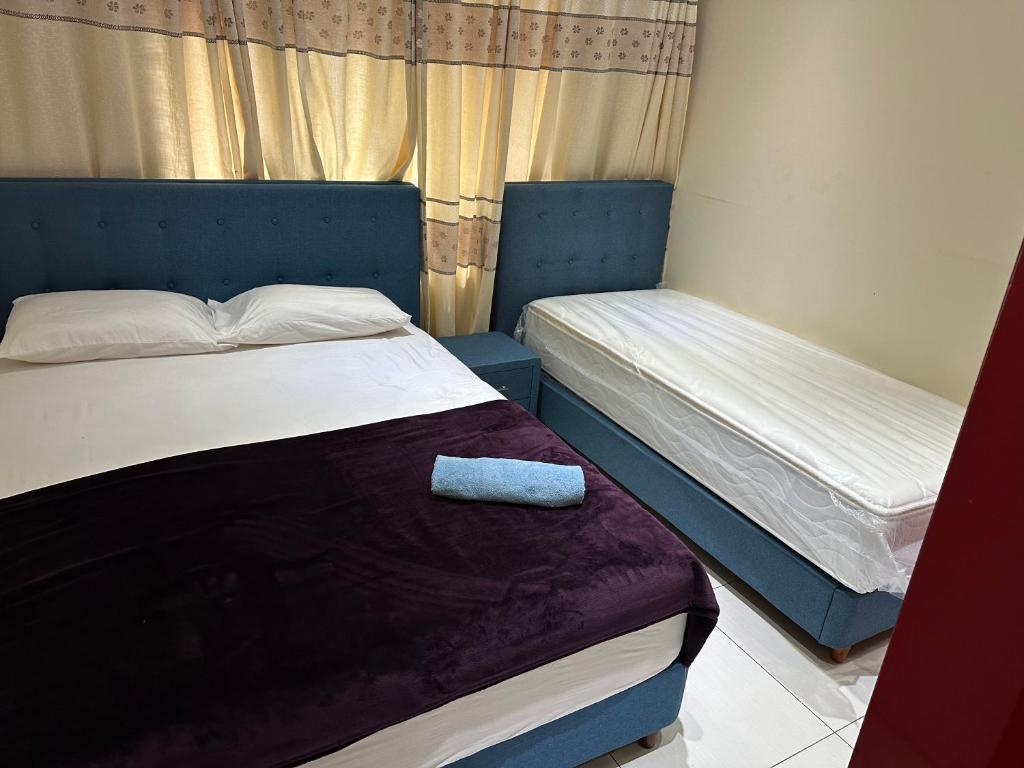 a bedroom with two beds and a blue headboard at Bhan Towers Apartment in Suva