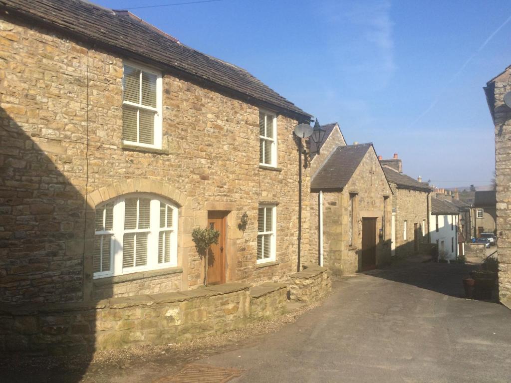 an old stone house with a street in a village at Masonic House, Alston in Alston