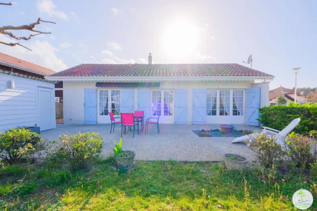 a blue and white house with pink chairs in a yard at Sanguinet Charmante maison avec jardin pour 6 personnes in Sanguinet
