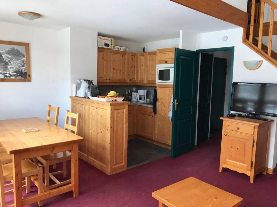 kuchnia z drewnianymi szafkami, stołem i telewizorem w obiekcie Valloire-Appt 3*-8 pers-Piscine-Rés. le Galibier w mieście Valloire