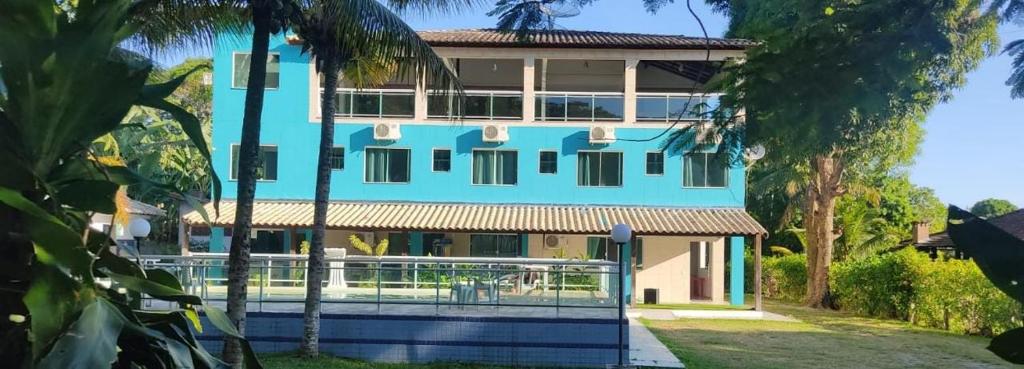 a blue building with palm trees in front of it at Pousada Del Mare di Ponta Negra in Maricá