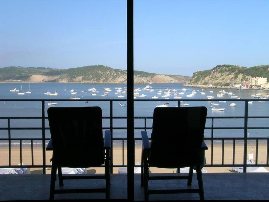 2 Stühle auf einem Balkon mit Blick auf das Wasser in der Unterkunft Apartamento em frente à Praia in São Martinho do Porto