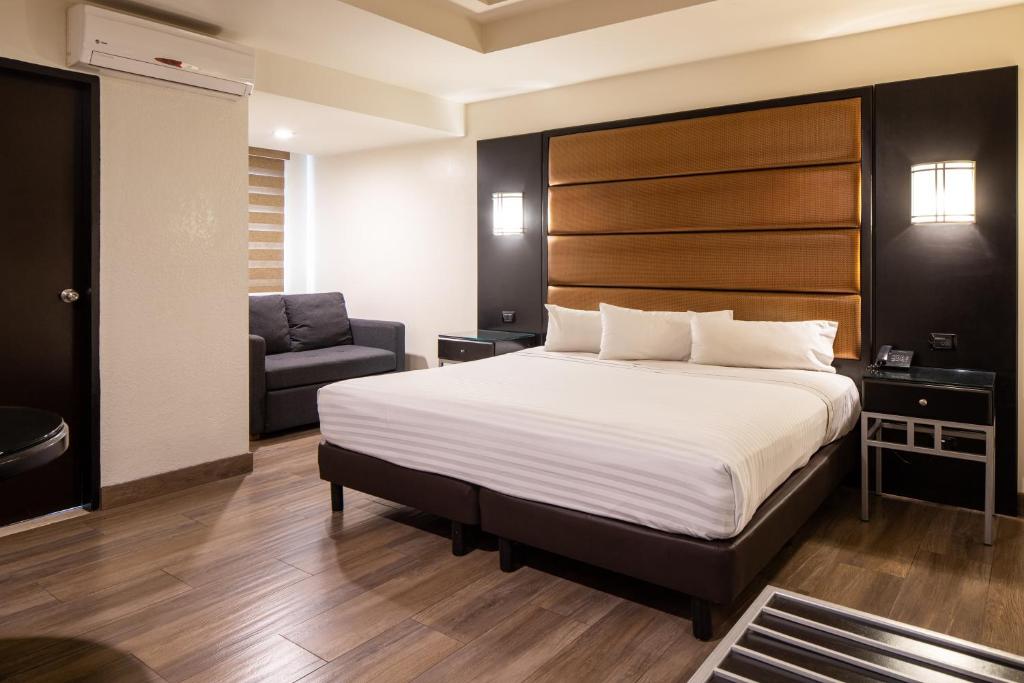 a hotel room with a bed and a chair at Hotel Astor Tijuana in Tijuana