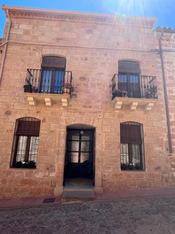 a brick building with three windows and a door at Casa Rural Verde Oliva in Baños de la Encina
