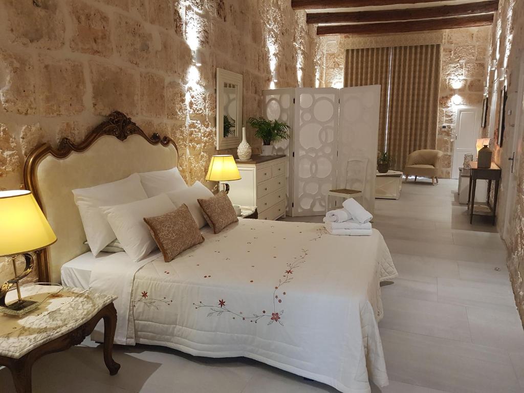 a bedroom with a white bed and a stone wall at Tal-Kampjin in Mellieħa