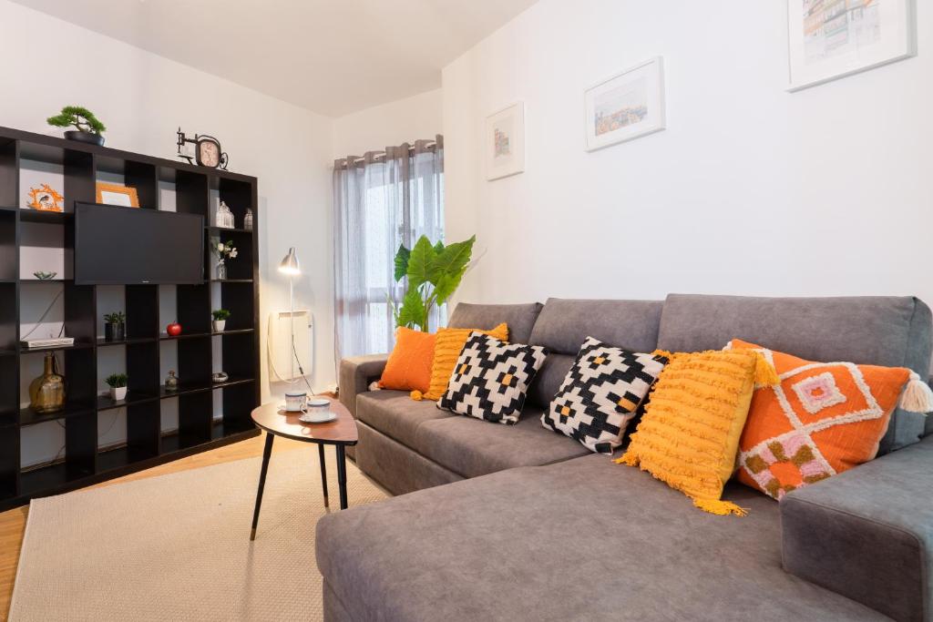een woonkamer met een grijze bank en kleurrijke kussens bij Apt Boavista 3bdr Casa da música in Porto