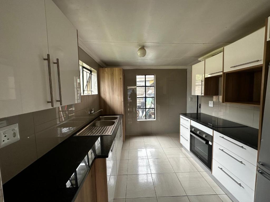 una cocina con armarios blancos y encimeras negras en Silverton Private Apartment en Pretoria