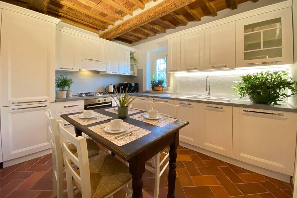 cocina con mesa de madera y armarios blancos en Viaggiare Smart [Wi-fi, TV HD, Spazio di lavoro, Parcheggio gratuito nella struttura,], en Capannori
