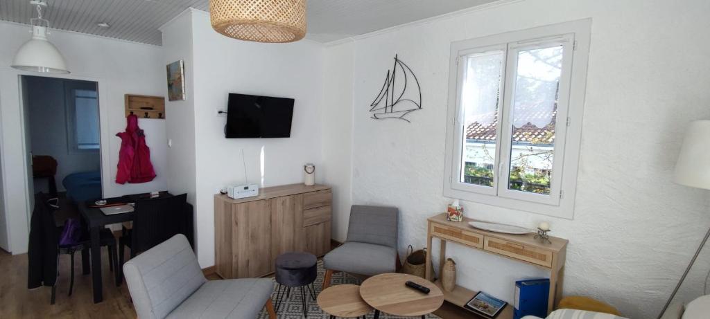 ein Wohnzimmer mit einem Sofa, einem Tisch und einem Fenster in der Unterkunft Spacious quiet nest with garden near the sea in La Tranche-sur-Mer