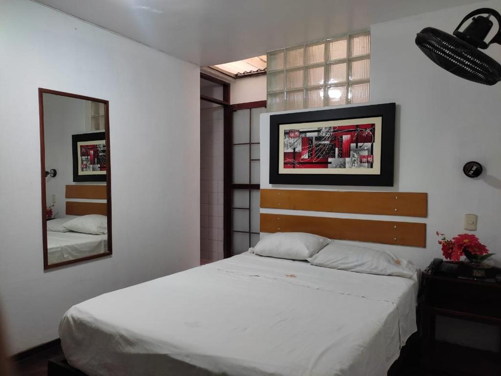 1 dormitorio con cama blanca y espejo en Hotel San Isidro, en Trujillo