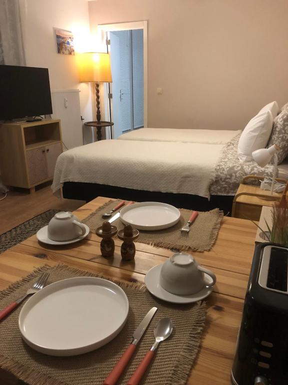 a table with plates and utensils and a bed at Pina's Appartment in Namur
