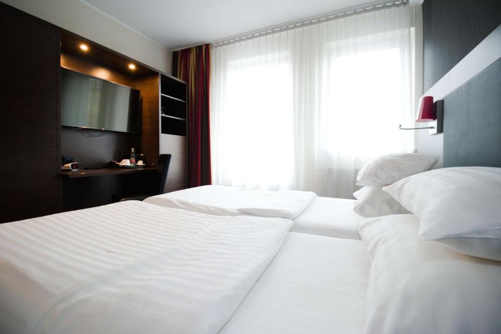 two white beds in a bedroom with a window at Best Western Plus Plaza Hotel Graz in Graz