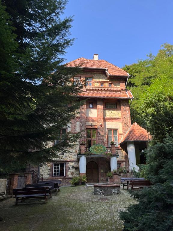 a large brick building with benches in front of it at Willa Starówka in Nałęczów