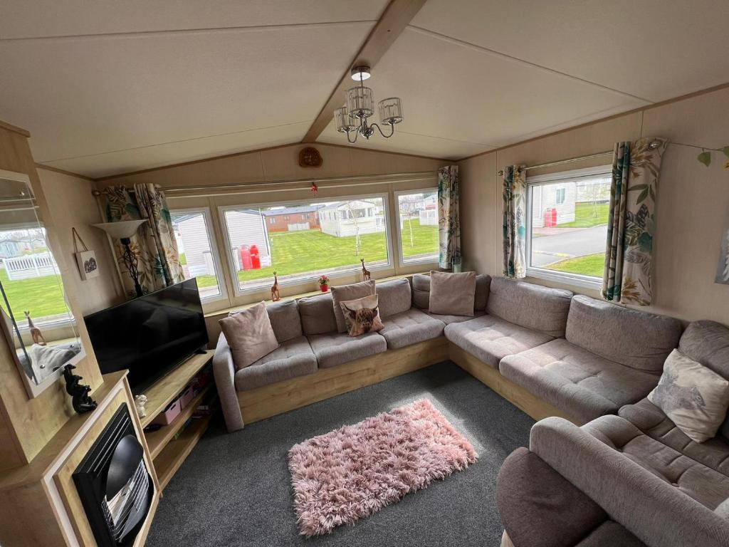 uma sala de estar com um sofá e uma televisão de ecrã plano em N and B caravan hire Flamingo Land em Kirby Misperton