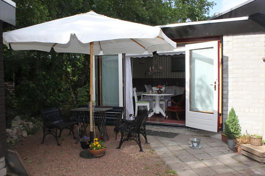 un patio con sombrilla, mesa y sillas en Bed and Breakfast Het Oude Bos, en Wijnjewoude