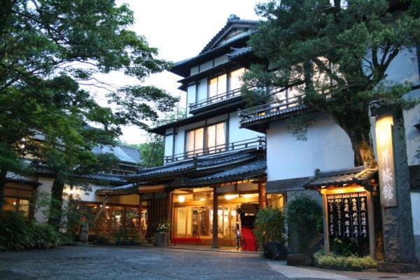 un grand bâtiment avec un arbre en face dans l'établissement Arai Ryokan, à Izu