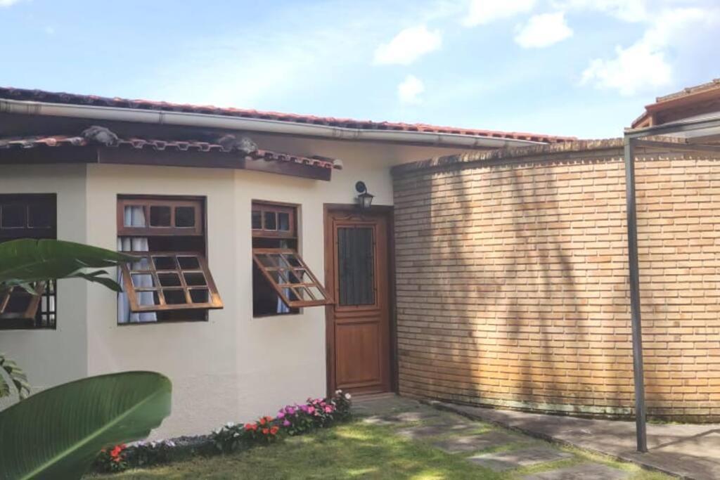 een huis met een bakstenen muur en een houten deur bij Centro - São Francisco Xavier - Casa Agradável in São Francisco Xavier