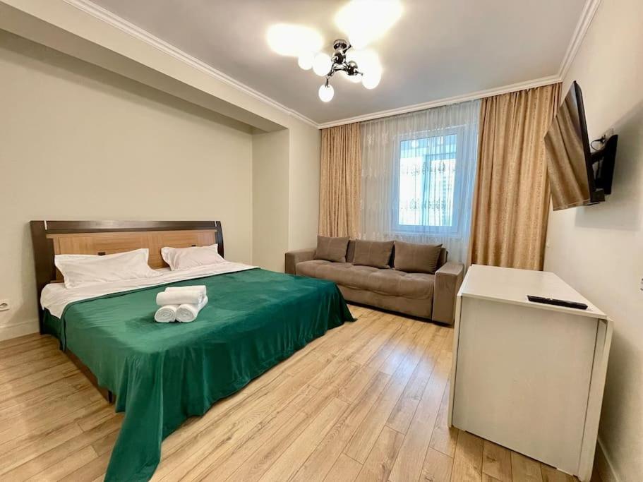 um quarto com uma cama verde e um sofá em Жк «Abay 130» комфорт и уют em Almaty