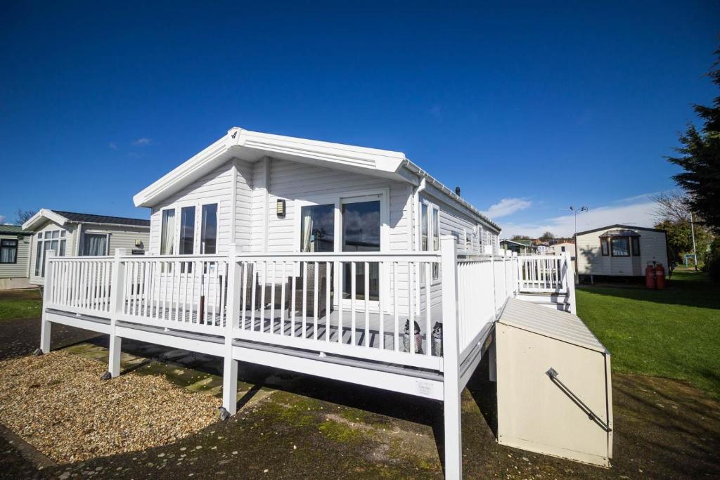 a white tiny house with a large porch at Beautiful 4 Berth Lodge With Decking At Manor Park In Hunstanton Ref 23038c in Hunstanton