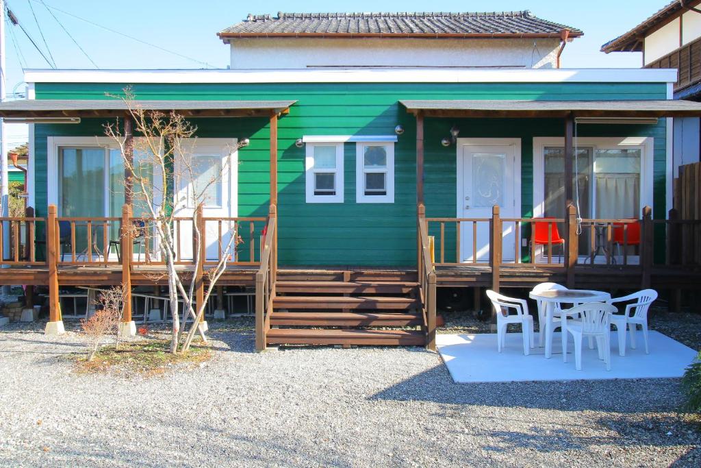 een groen huis met een tafel en stoelen ervoor bij Yuuwa Guesthouse in Mifune