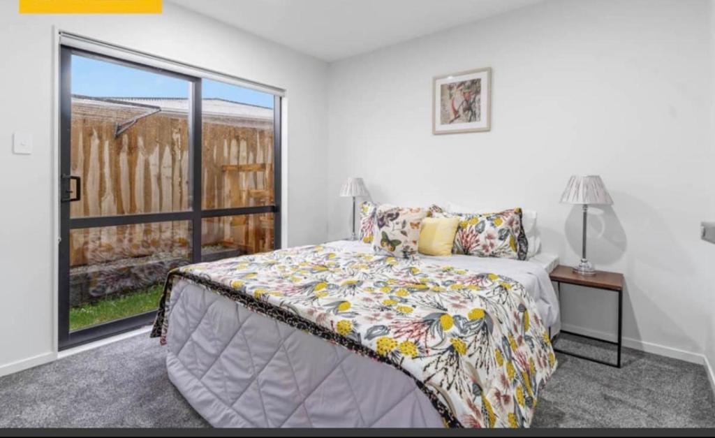 Private room near Auckland Airport في أوكلاند: غرفة نوم بسرير ونافذة كبيرة