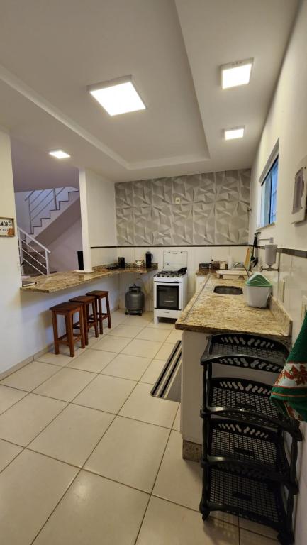 a large kitchen with white tile floors and counters at Casa confortável pertinho da praia com garagem e quintal in Rio das Ostras