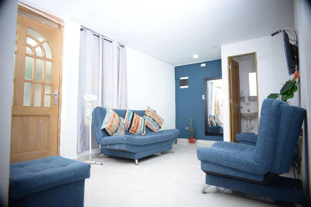 ein Wohnzimmer mit zwei blauen Stühlen und einer Tür in der Unterkunft casa nogal in Medellín